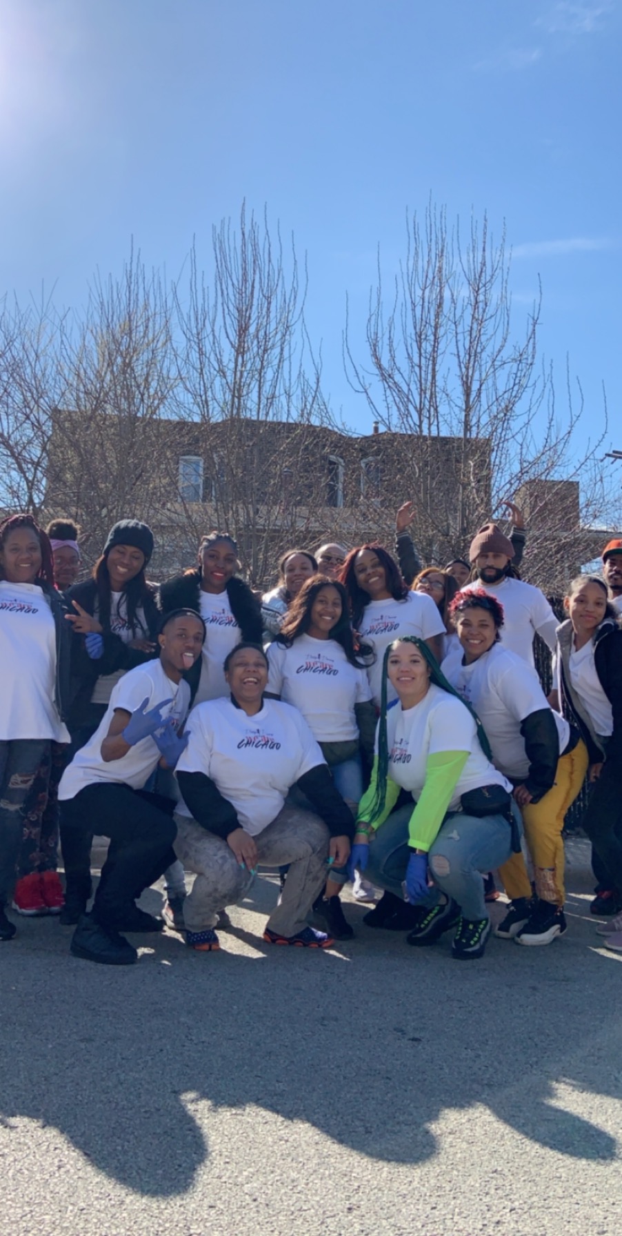 Large group of smiling volunteers gathered outdoors after a community giveback